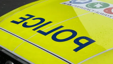 The fluorescent yellow bonnet of a car, with reversed lettering spelling the word police.