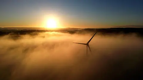 A wind turbine is shrouded in fog (stock image).