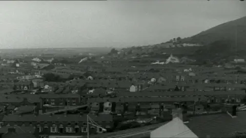 A black and white aerial image of the town of Port Talbot and its rows of terraced streets with a hill in the background