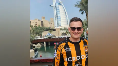 Miles Fletcher Miles Fletcher pictured in Dubai wearing his Hull City shirt. He is standing in front of the Burj Al Arab luxury hotel.