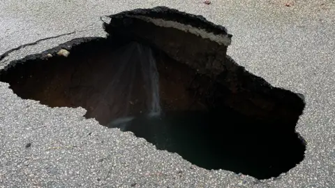 A dark sinkhole where water can be seen inside