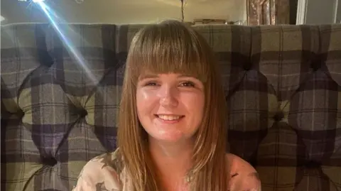 Supplied A close-up photo of Rebecca Guy. She is sitting on a patterned chair and smiling into the camera.