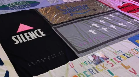 A close up view of a panel of the quilt with various tributes and names - including Sylvester, Peter Davis and Andrew