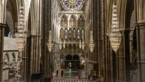 Getty Images An interior view of Westminster Abbey showing ornate stained glass windows, stonework, archways and chandeliers