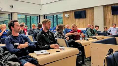 University of Gloucestershire Trainee referees in a lecture hall sat at tables with note pads and pens