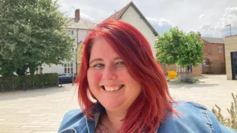 Martin Heath/BBC Becky Lane with long red hair wearing a blue jacket