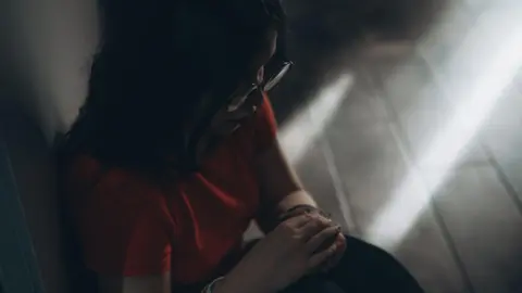 Girl stuck inside a building with light pouring in the window. This is a stock image