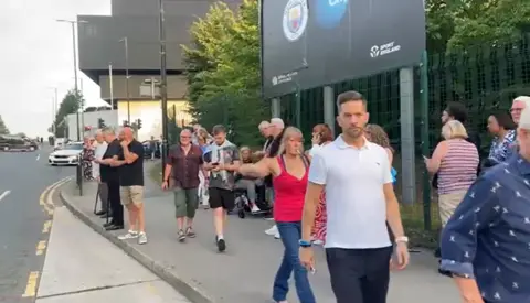 Fans streaming out of the Co Op Live arena in Manchester. They are walking up the road close to the venue.
