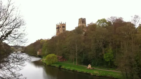 BBC Durham Cathedral poking out of trees on a riverbank