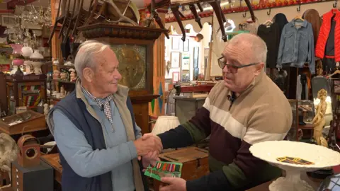 A man hands over a set of five world war two medals in an antique shop 