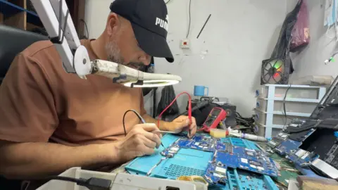Computer repair technician works on a motherboard in Gaza