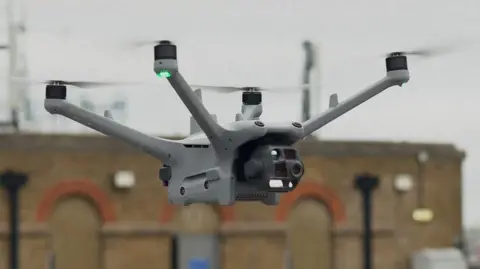 A close up of a drone in flight in an urban setting.