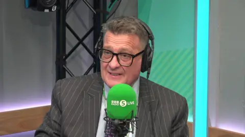 Karl Turner in a pinstripe suit sat in the BBC Radio 5 Live studio 
