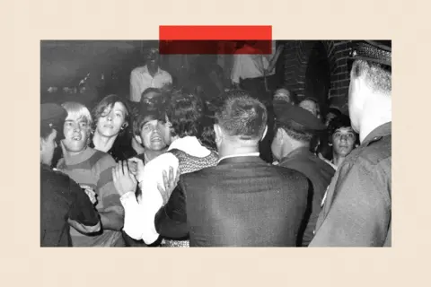 NY Daily News Archive via Getty Images A black and white image of police raiding the Stonewall Inn