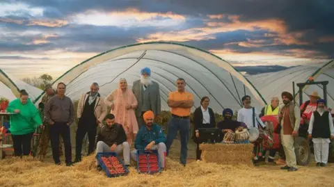 Handout An image from the film showing workers standing in front of polytunnels used to grow strawberries. Some of the Punjabi workers are wearing Indian clothing.