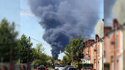 Marin Corneliu Mihail A plume of black smoke viewed from a residential street nearby
