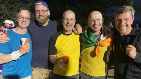 Alistair Goulding The five members of team Stockholm Syndrome pictured together at the European Championships in 2024. They are all smiling at the camera, two of them are holding pints of beer in their hands.