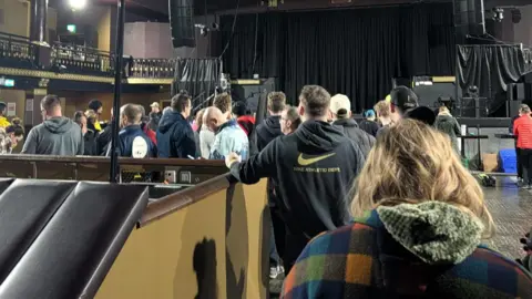 Laura O'Neill/BBC A queue of people wait for tickets inside the 02 Ritz. 