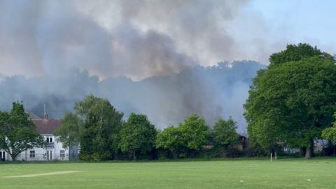 Clouds of smoke next to a house and field
