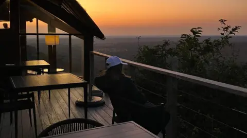 Supplied Lily-Rae pictured sitting on a balcony at sunset. She is looking at the sky.