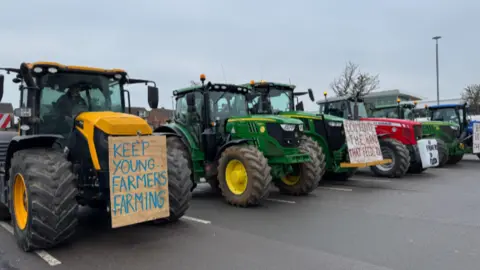 A row of tractors bearing signs, parked up.