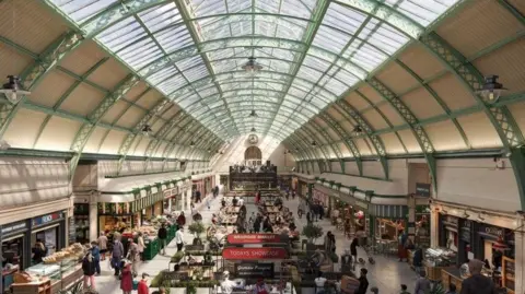 Newcastle City Council An elevated view of the Grainger Market, looking down at an arcade featuring a range of stalls selling plant, fruit and veg, as well as cafes and bakeries. Above is the barrelled glass roof.