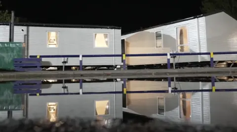 Kevin Saddington/BBC. Imagen reflejada del agua bajo las caravanas en el Acuódromo de Billing. La imagen fue tomada de noche.