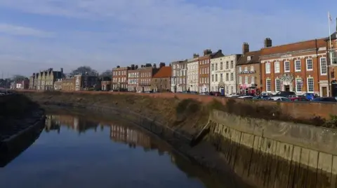 Tim Heaton/Geograph A row of Georgian townhouses line the street, which is next to a wide river.