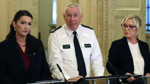 PA Media Emma Little Pengelly, Jon Boutcher and Michelle O'Neill stand side by side at a podium in Stormont