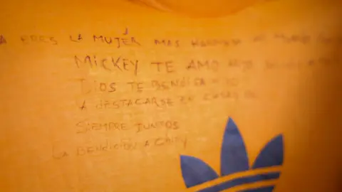 A message written in black ink on a bright orange t-shirt 