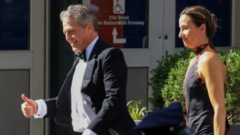 US actor Hugh Grant and his wife Anna Elisabet Eberstein wear formalwear as they walk up to the entrance of Madison Square Garden.