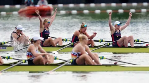 PA Media Four women in canoe - two with their arms up in the background, the opponent's crew in the foreground