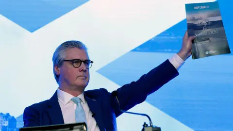 Malcolm Offord, Leader of Reform UK Scotland holds up a copy of the manifesto after delivering a speech at Ingliston Country Club and Hotel on March 19, 2026 in Bishopton, Scotland