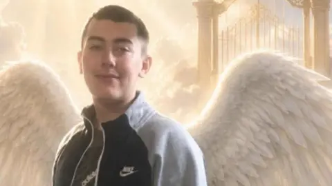 A photo of Joshua Oxley with angel wings. He has short dark hair and dark eyes.