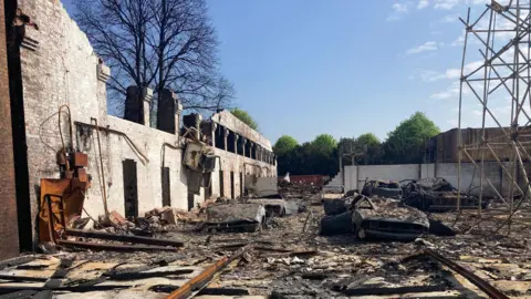 The site of the former Hangar 3 Cafe at Old Sarum Airfield. It has been devastated by a fire and there is debris all over the ground.