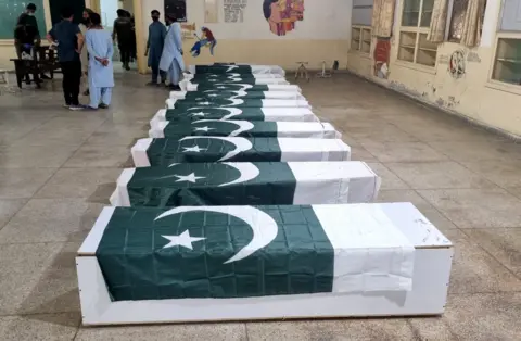 A row of coffins, draped with Pakistan's flag, are laid out at a funeral mass for those killed in a strike on a madrasa in Bahawulpur on 7/5/2025
