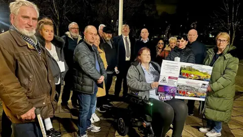 Up to a dozen campaigners gather to protest about the development with one in a wheelchair