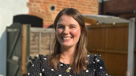 Imogen Pearson sits in front of her house with a fence and a shed in the background.