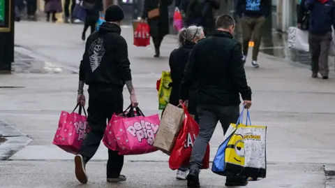 Jacob King/PA Wire Some people walking down Worcester High Street, carrying shopping bags.