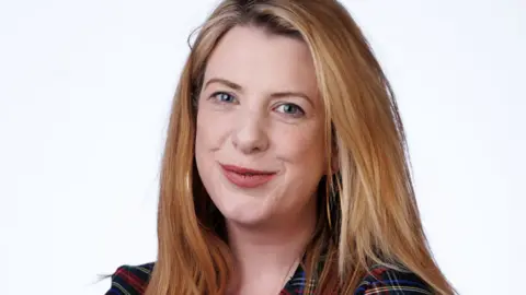 A head and shoulders shot of a smiling Nicky Brennan, who has fair hair