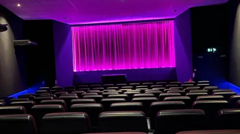 Empty Kavanagh Cinema screen one with curtains drawn and backlit purple