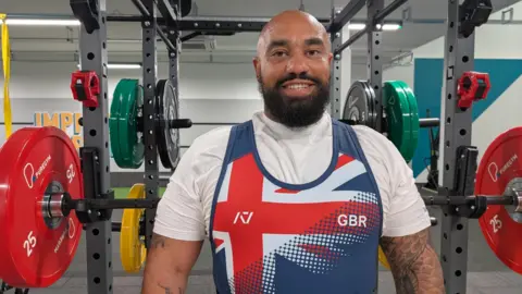 Ram stood in his Team GB kit, surrounded by barbells