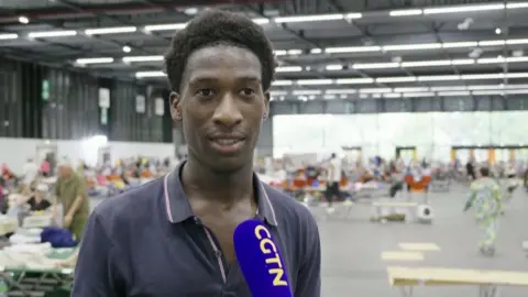 Jean Philippe, an evacuee, stands in front of a microphone