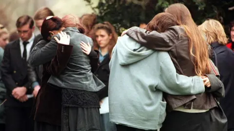 PA Media Groups of smartly dressed young people hugging in a churchyard at Leah Betts' funeral.