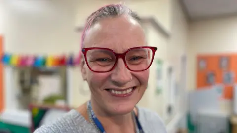 Kelly has pink hair and glasses