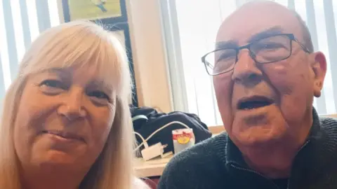 Family photo A selfie of Eve, 63, and Dave, 82. Eve has long blonde hair with a fringe. Dave has dark hair and glasses.