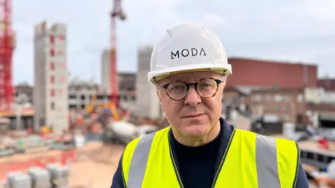 BBC Planning director James Blakey wearing a hard hat and high-vis jacket, standing in an apartment development in Digbeth, Birmingham 