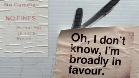 Claire Cavanagh Pieces of paper with opposing opinions on them about the East Bristol Low Traffic Neighbourhood scheme. One reads: "No cameras, no fines! Barton Hill is not a prison". The other one reads: "Oh, I don't know, I'm broadly in favour". 