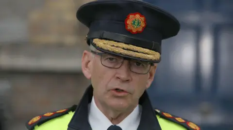 PA Media Garda Commissioner Drew Harris speaking to the media at Garda headquarters in Dublin after Irish police officer Kevin Flatley was killed at a checkpoint in Dublin after being struck by a motorbike. He is wearing his garda hat and glasses.