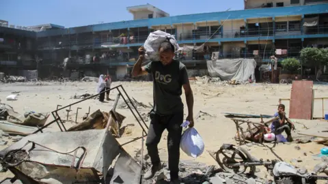Reuters Palestinian man Bilal Khrouat carries his belongings to a shelter inside an Unrwa school in Jabalia, in the northern Gaza Strip (2 June 2024)